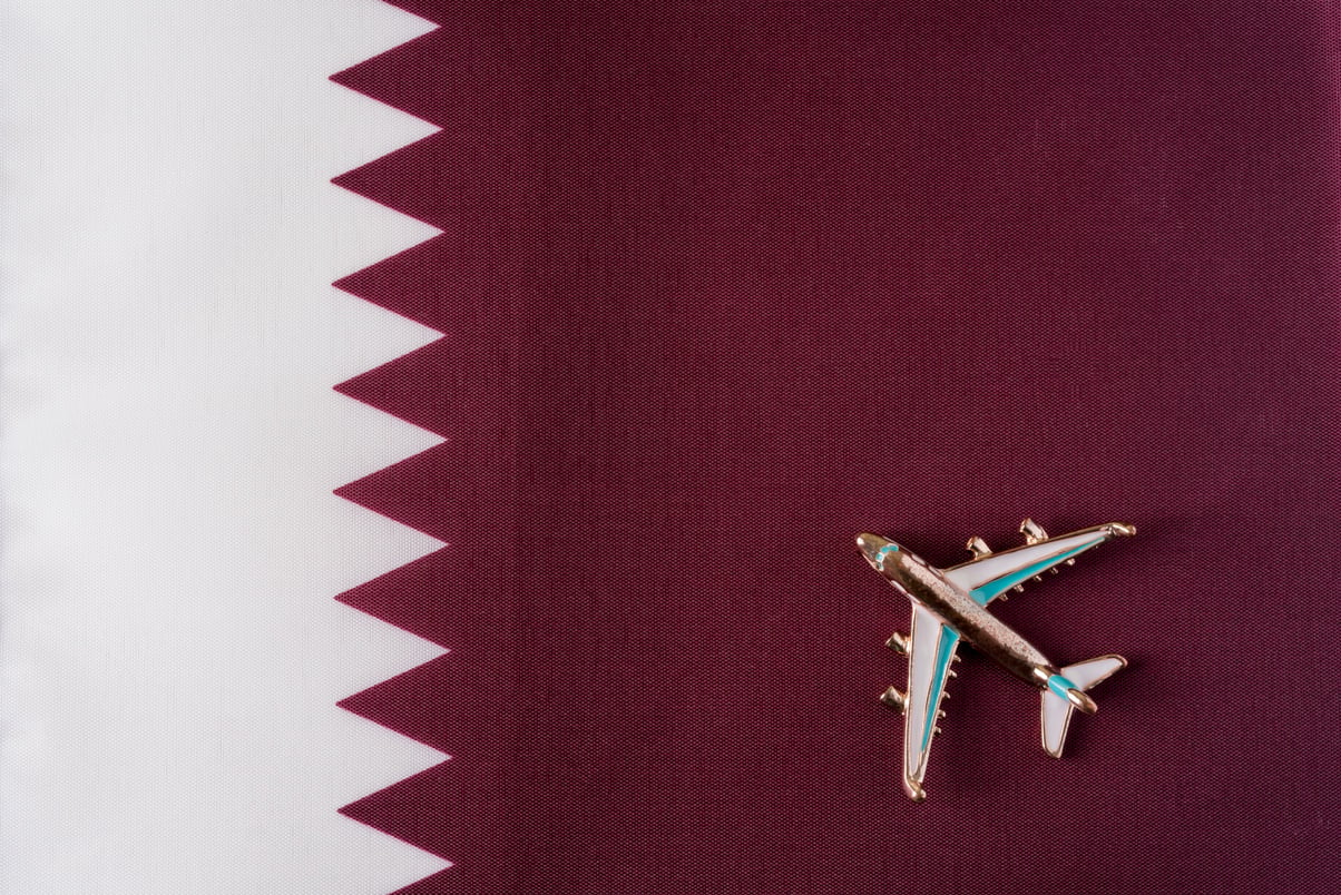 Plane over the Flag of Qatar Travel Concept.